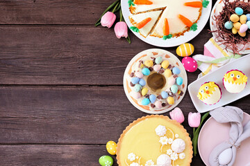 Fototapeta na wymiar Easter or spring dessert food side border. Above view over a dark wood background. Lemon tart, cupcakes, Easter egg and carrot cakes and a collection of sweets. Copy space.