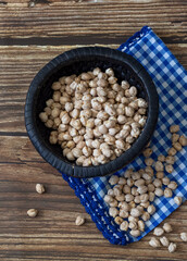 Raw chickpeas spread on a wooden table and a blue tablecloth view from above
