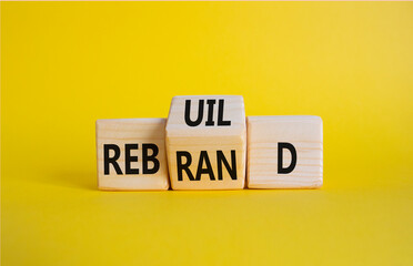 Rebuild and Rebrand symbol. Wooden cubes with words Rebrand and Rebuild. Beautiful yellow background. Rebuild Rebrand and Business concept. Copy space