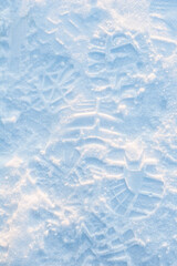 Close-up vertical photo of shoe prints in the snow.