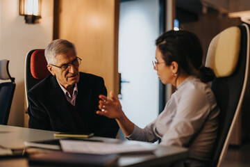 Senior and younger business people engaged in discussion during a collaborative office meeting. Showcasing teamwork and multigenerational workplace interaction.
