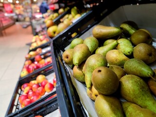 Close up shot of pears lying in a plastic crate on a supermarket shelf at the fruit and vegetable...