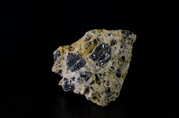 Emerald stone inclusions in rock mass on black background. 