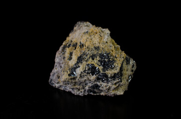 Emerald stone inclusions in rock mass on black background.