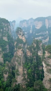 Famous tourist attraction of China - Zhangjiajie stone pillars cliff mountains in fog clouds at Wulingyuan, Hunan, China. With camera pan
