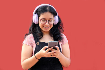 Female Latina teenager of 17 years old uses her cell phone and audio to connect to music, podcast...