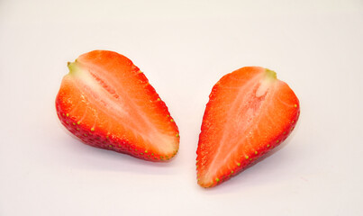 large ripe red strawberry cut in half on a light background