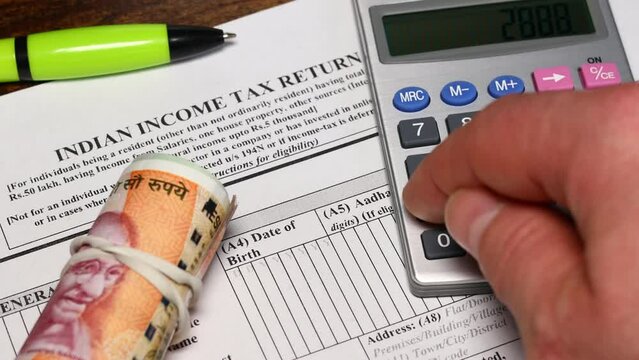annual tax return in India, Concept, settling tax with the office, Tax form, Man calculates the tax due on a calculator, roll of Indian rupees