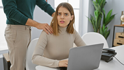 A worried woman with her male colleague in an office, conveying workplace discomfort and possible harassment.