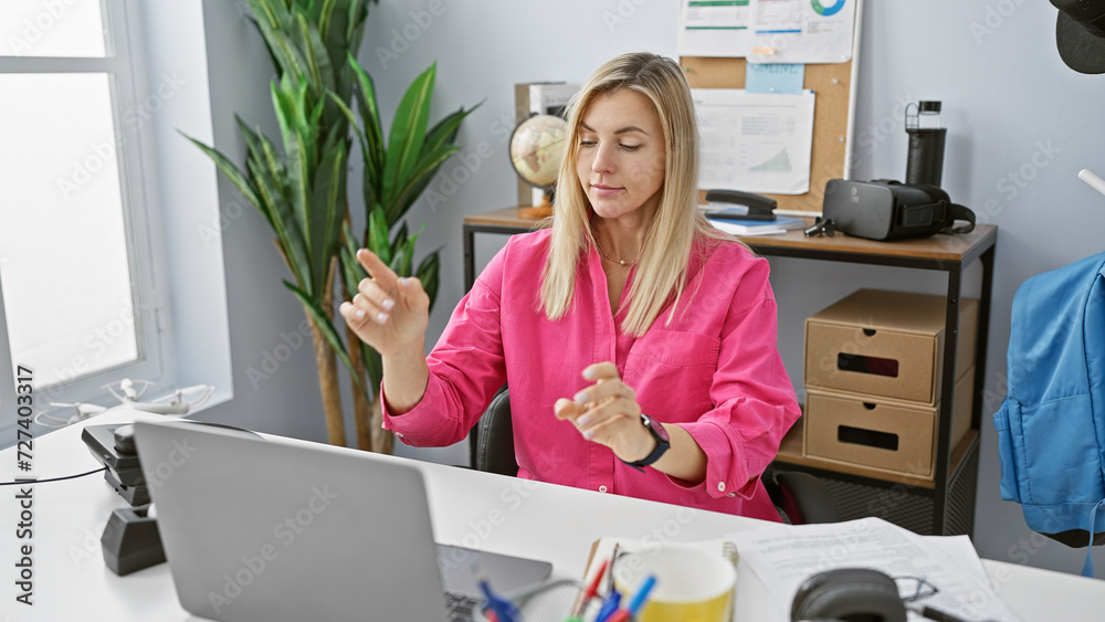 Sticker caucasian woman in pink blouse multitasking in a modern office, using a laptop and smartphone simult