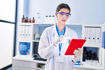 Young beautiful hispanic woman scientist using touchpad at laboratory