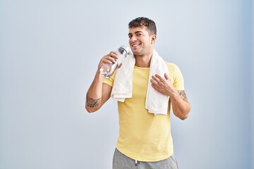 Young hispanic man drinking water standing at sport center