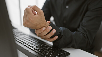 Handsome businessman with beard in office suffering wrist pain