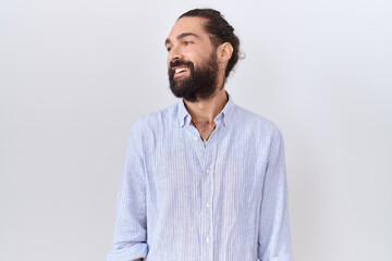 Fototapeta premium Hispanic man with beard wearing casual shirt looking away to side with smile on face, natural expression. laughing confident.