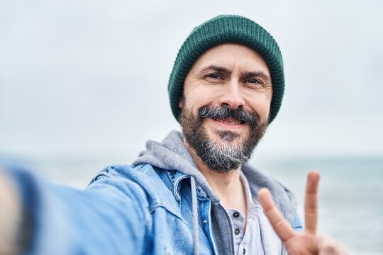 Young bald man smiling confident making selfie by camera at seaside