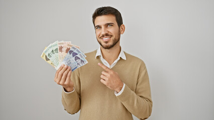 A smiling young hispanic man pointing at korean won currency in his hand against a white background.