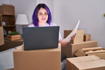 Young beautiful plus size woman using laptop reading document at new home