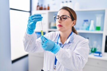 Young beautiful hispanic woman scientist holding test tube at laboratory