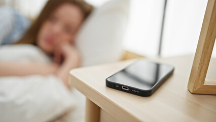 Young blonde woman looking smartphone with sad expression at bedroom