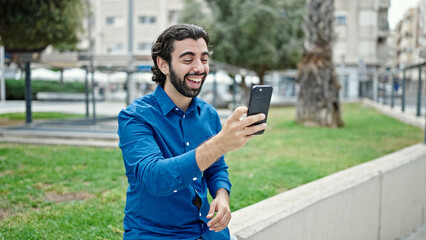 Young hispanic man smiling confident having video call at park