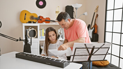 Passionate hispanic man and woman musicians engrossed in a melodious piano lesson together at a cozy music studio