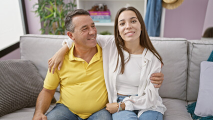 Obraz premium Joyful family time, father and daughter sharing a heartwarming hug, sitting on the sofa at home, their smiles radiating love and happiness