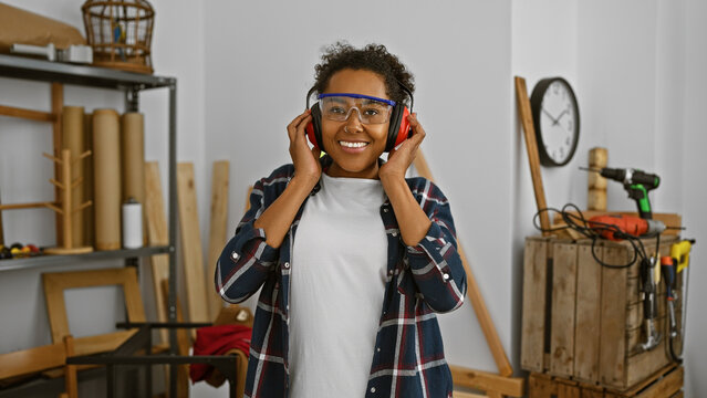 Smiling woman with safety glasses and headphones in a woodshop