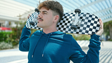 Young hispanic man holding skate with serious face at park © Krakenimages.com