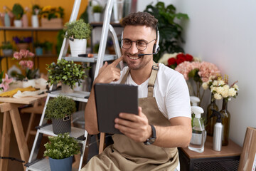 Hispanic man with beard working at florist shop doing video call smiling happy pointing with hand and finger