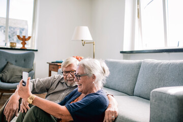 Senior couple using a smart phone at home in the living room