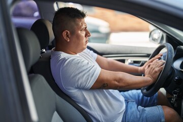 Young latin man stressed driving car at street