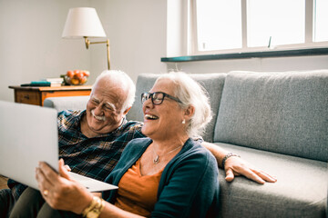 senior couple using a laptop at home in the living room