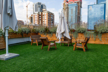 Urban rooftop garden with wooden furniture, artificial grass, and cityscape backdrop in Ramat Gan, Israel