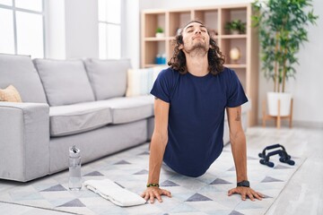 Young hispanic man training yoga at home