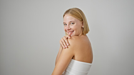 Obraz premium Young blonde woman smiling confident touching shoulder over isolated white background