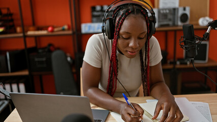 In the heart of a radio studio, a beautiful african american woman musician sits at the table,...