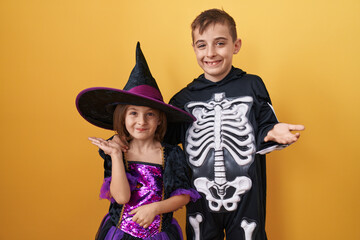 Excited little brother and sister in halloween costumes, celebrating a triumphant win with joyful...