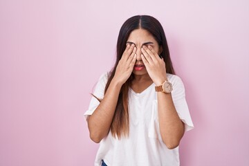 Young arab woman standing over pink background rubbing eyes for fatigue and headache, sleepy and...