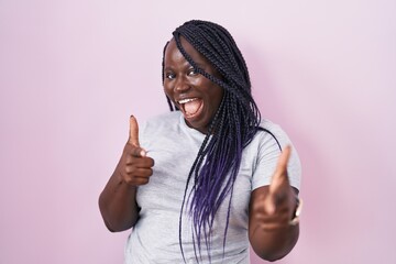 Young african woman standing over pink background pointing fingers to camera with happy and funny face. good energy and vibes.