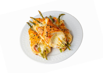 Baked green asparagus with ham and cheese in puff pastry sprinkled with sesame seeds and green basil leaves.