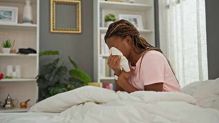 African american woman sitting on bed with being sick at bedroom