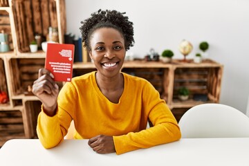 African american woman holding switzerland passport sitting on table at home