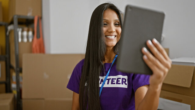 Young latin woman volunteer using touchpad smiling at charity center