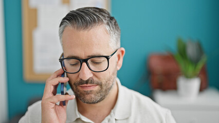 Grey-haired man business worker talking on smartphone at the office