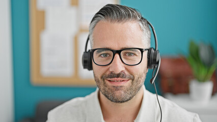 Grey-haired man business worker wearing headphones at the office