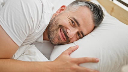 Fototapeta na wymiar Grey-haired man smiling confident lying on bed at bedroom