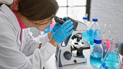 Determined young hispanic woman scientist, with beautiful hairstyle, engrossed in serious research...