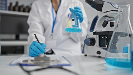 Intriguing glance at the seasoned hands of a senior woman scientist meticulously taking notes in the lab, engrossed in her remarkable test tube experiment