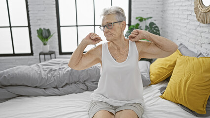 Elderly grey-haired woman enjoying a morning stretch, waking up in the comfort of her bedroom, at...