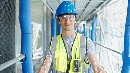Young hispanic man architect smiling confident standing at construction place